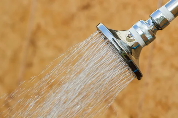 Glänzende Edelstahl-Kopfdusche unter fließendem Wasser. — Stockfoto