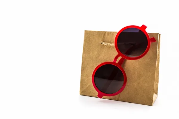 Schicke rote Sonnenbrille hängt an brauner Einkaufstasche. — Stockfoto
