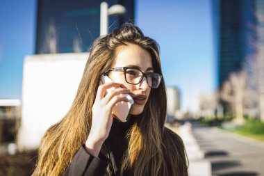 Finansal alanda cep telefonuyla konuşan gözlüklü genç beyaz kız yöneticisinin portresi..