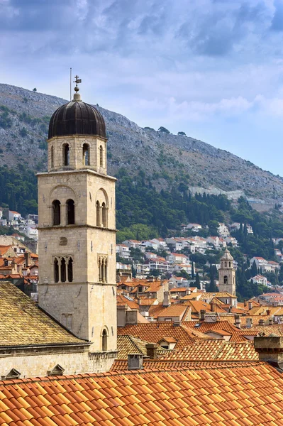 Bell tower a červeno oranžové střechy na pozadí hory a — Stock fotografie