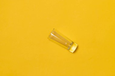 Sarı arkaplanda tekila için shot bardağının üst görüntüsü