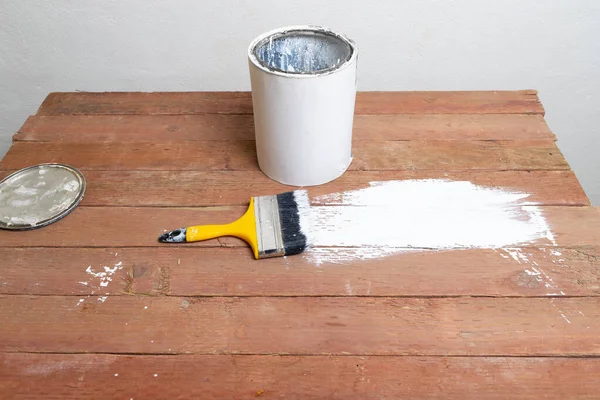 white paint pot and brush on wooden planks, renovation concept