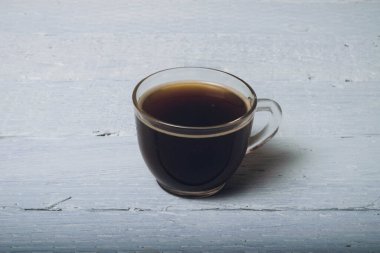 Kahve dükkanındaki tahtalar üzerinde şeffaf bir fincan kahve.