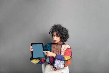 Güzel, Latin, günlük kıyafetler giyen, tablet ekranı gösteren genç bir kadın.