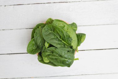 Beyaz tahtalar üzerinde organik ıspanak yapraklarının üst görüntüsü.