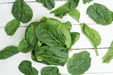 Beyaz tahtalar üzerinde organik ıspanak yapraklarının üst görüntüsü.