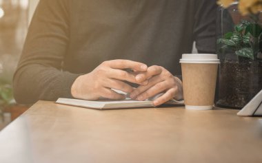 Not defterinde kalem olan bir erkek eli. Kahve için deftere yazarken duraklat.