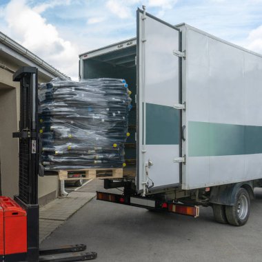 Gündüz vakti forklift kullanarak malı kamyona yüklemek. Malların nakliyesi.