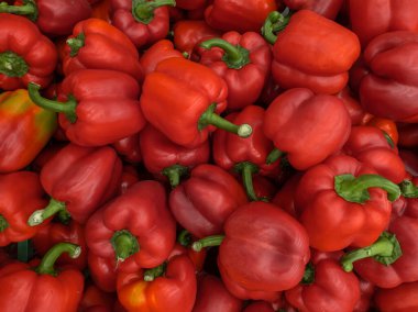 Çok sayıda tatlı kırmızı biberin (Capsicum annuum) bir arka planı. Market vitrinindeki sebzelerden. Kırmızı biber hasat ediliyor.