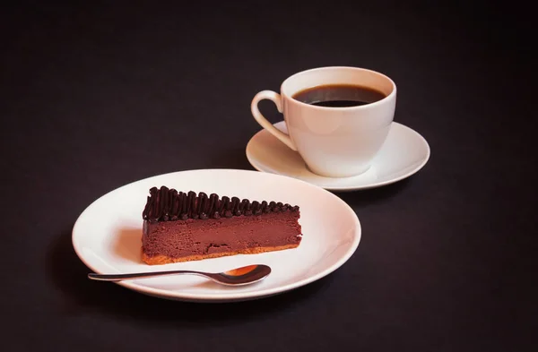 チョコレートソースと黒コーヒーのカップとチョコレートチーズケーキ暗い背景に チーズケーキの選択的焦点 — ストック写真