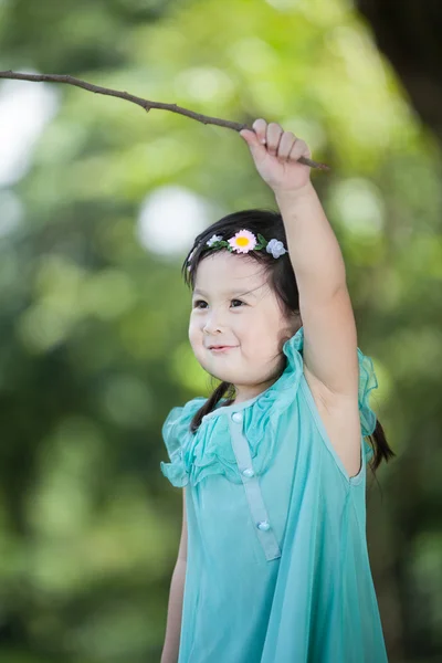 Little Asian girl playing branch of tree in the garden — Stock Photo, Image
