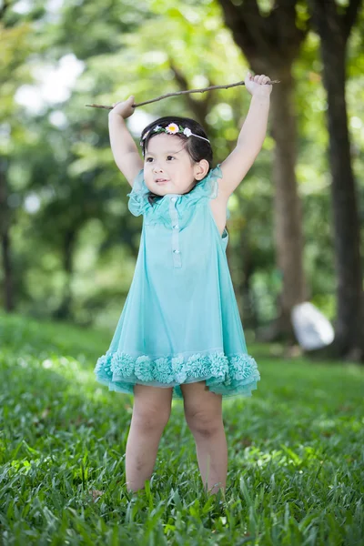 Маленькая азиатка, играющая на ветке дерева в саду — стоковое фото