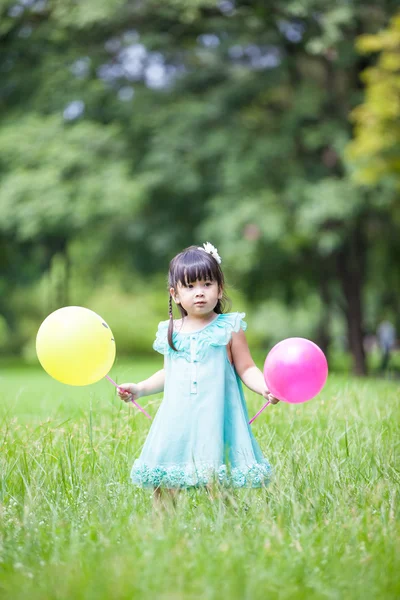 Liten asiatisk tjej spelar ballong i trädgården — Stockfoto