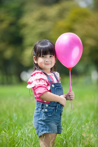 Маленькая азиатка играет на воздушном шаре в саду — стоковое фото