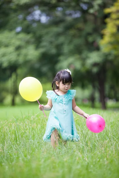 Piccola ragazza asiatica che gioca palloncino in giardino — Foto Stock