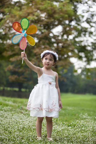 Liten söt flicka i vit klänning spelar vinden rullar leksak — Stockfoto