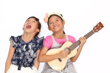küçük Asyalı kızlar wh bir şarkı ve ukulele iskambil izole şarkı
