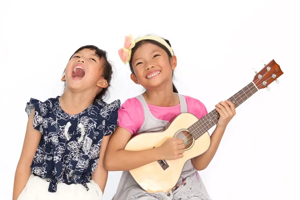 Little asian girls sing a song and playing ukulele isolate on wh — Stock Photo, Image