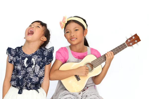 Little asian girls sing a song and playing ukulele isolate on wh Stock Photo