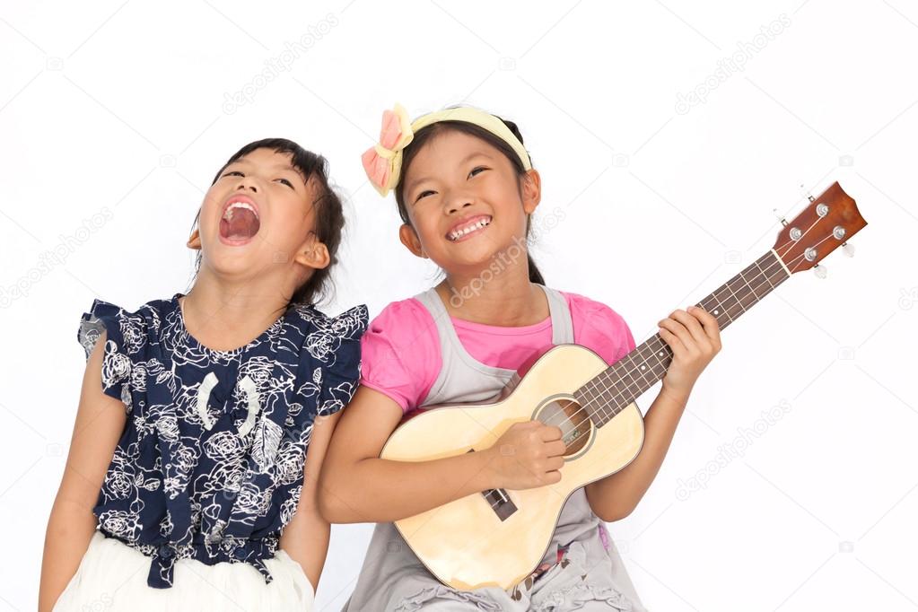 Little asian girls sing a song and playing ukulele isolate on wh