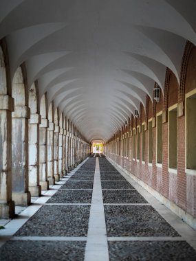 Bir tünel oluşturan kolonları ve kemerleri olan koridor. Aranjuez 'deki Casa de los Ninos' ta. Görkemli binanın etrafındaki yol, düzenlenmiş fotoğraf.