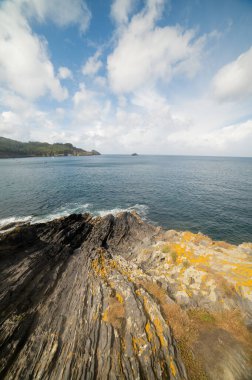 Rocky cliffs, some covered in vegetation, dropping into the ocean