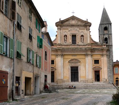 Yalnız bisikletçi, Fransa 'nın terk edilmiş meydanındaki Roma Katolik kilisesinin önünde dinleniyor..