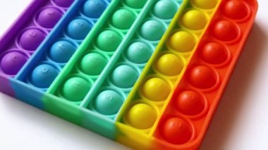 Çocuklar için gökkuşağı anti-stresli parmak itme oyuncağı beyaz arka planda izole edilmiş.