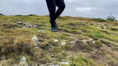 Bir turist yürüyüş botlarıyla sırt çantasıyla dağa tırmanıyor. Turizm ve aktif yaşam tarzı kavramı