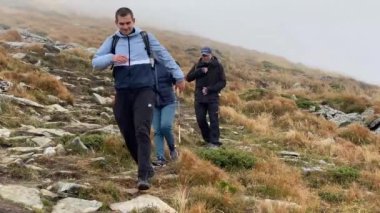 Ivano-Frankivsk, Ukrayna - 12 Ekim 2021: Bir grup turist sırt çantaları ve yürüyüş çubuklarıyla dağa tırmanıyor