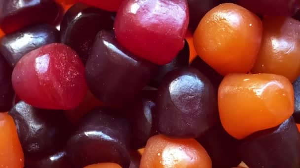 Κοντινή υφή κόκκινων, πορτοκαλί και μοβ πολυβιταμινών gummies σε λευκό φόντο. Υγιεινός τρόπος ζωής — Αρχείο Βίντεο