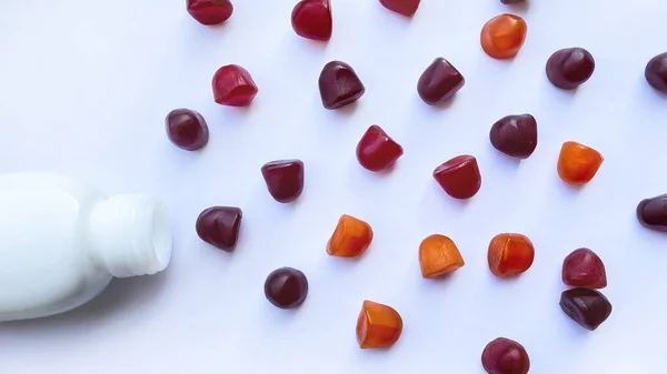 Ομάδα κόκκινων, πορτοκαλί και μωβ πολυβιταμινών gummies με το μπουκάλι απομονωμένο σε λευκό φόντο. — Φωτογραφία Αρχείου