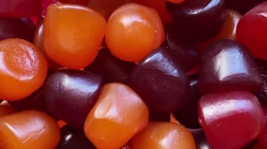 Beyaz zemin üzerinde kırmızı, turuncu ve mor multivitamin sakızlarının yakın çekim dokusu. Sağlıklı yaşam tarzı kavramı