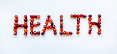 Bir grup kırmızı, turuncu ve mor multivitamin sakızı sağlık sözcüğü şeklinde dizilmiştir.