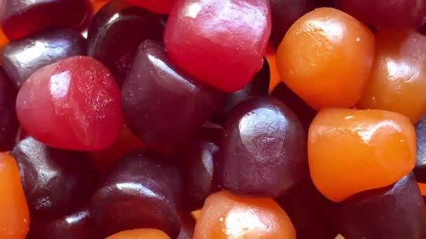 Κοντινή υφή κόκκινων, πορτοκαλί και μοβ πολυβιταμινών gummies σε λευκό φόντο. Υγιεινός τρόπος ζωής — Αρχείο Βίντεο
