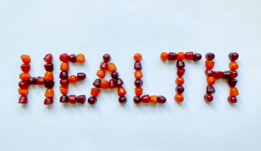Bir grup kırmızı, turuncu ve mor multivitamin sakızı sağlık sözcüğü şeklinde dizilmiştir.
