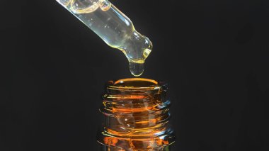 Bir damla yüz serumu olan boru ya da yüz için yağ ve güzel siyah arka planda hyaluronik asit, yakın plan.