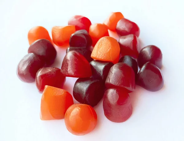 Beyaz zemin üzerinde kırmızı, turuncu ve mor multivitamin sakızlarının yakın çekim dokusu. Sağlıklı yaşam tarzı kavramı