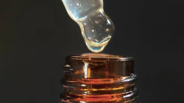 Bir damla yüz serumu olan boru ya da yüz için yağ ve güzel siyah arka planda hyaluronik asit, yakın plan.