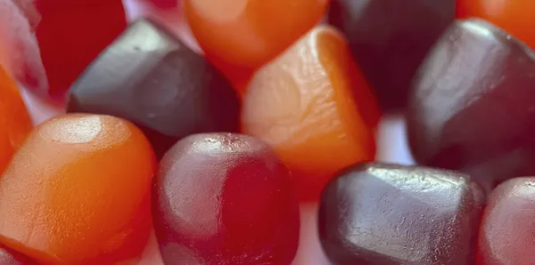 Focus.Close-up texture di gomme multivitaminiche rosse, arancioni e viola su sfondo bianco — Foto Stock