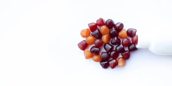 Gruppo di gomme multivitaminiche rosse, arancioni e viola con la bottiglia isolata su sfondo bianco. — Foto Stock