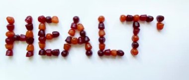 Bir grup kırmızı, turuncu ve mor multivitamin sakızı sağlık sözcüğü şeklinde dizilmiştir.