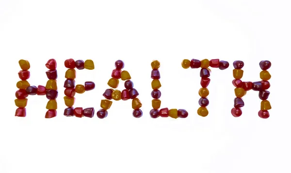 Група червоних, апельсинових і фіолетових мультивітамінних жуй, викладених у вигляді слова "здоров'я" — стокове фото