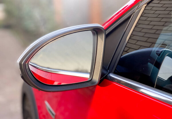 Close-up car mirror for viewing the blind spots of a red car. Car details