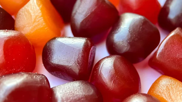 Foco seletivo.Textura close-up de gomas multivitamínicas vermelhas, laranja e roxas sobre fundo branco — Fotografia de Stock