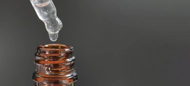 Bir damla yüz serumu olan boru ya da yüz için yağ ve güzel siyah arka planda hyaluronik asit, yakın plan.