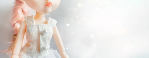 Кукла в белом платье с розовыми волосами стоит на волшебном фоне боке. — стоковое фото