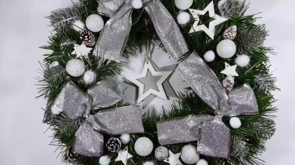 Різдвяний вінок, що прикрашає вхідні двері на свята з ялини, срібних луків, зірок та різдвяних кульок ізольовані на білому тлі — стокове відео
