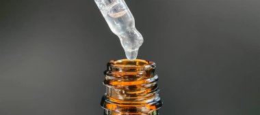 Bir damla yüz serumu olan boru ya da yüz için yağ ve güzel siyah arka planda hyaluronik asit, yakın plan.