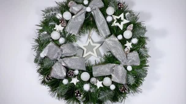 Świąteczny wieniec zdobiący frontowe drzwi na święta wykonane ze świerku, srebrnych kokardek, gwiazd i bożonarodzeniowych kulek odizolowanych na białym tle — Wideo stockowe